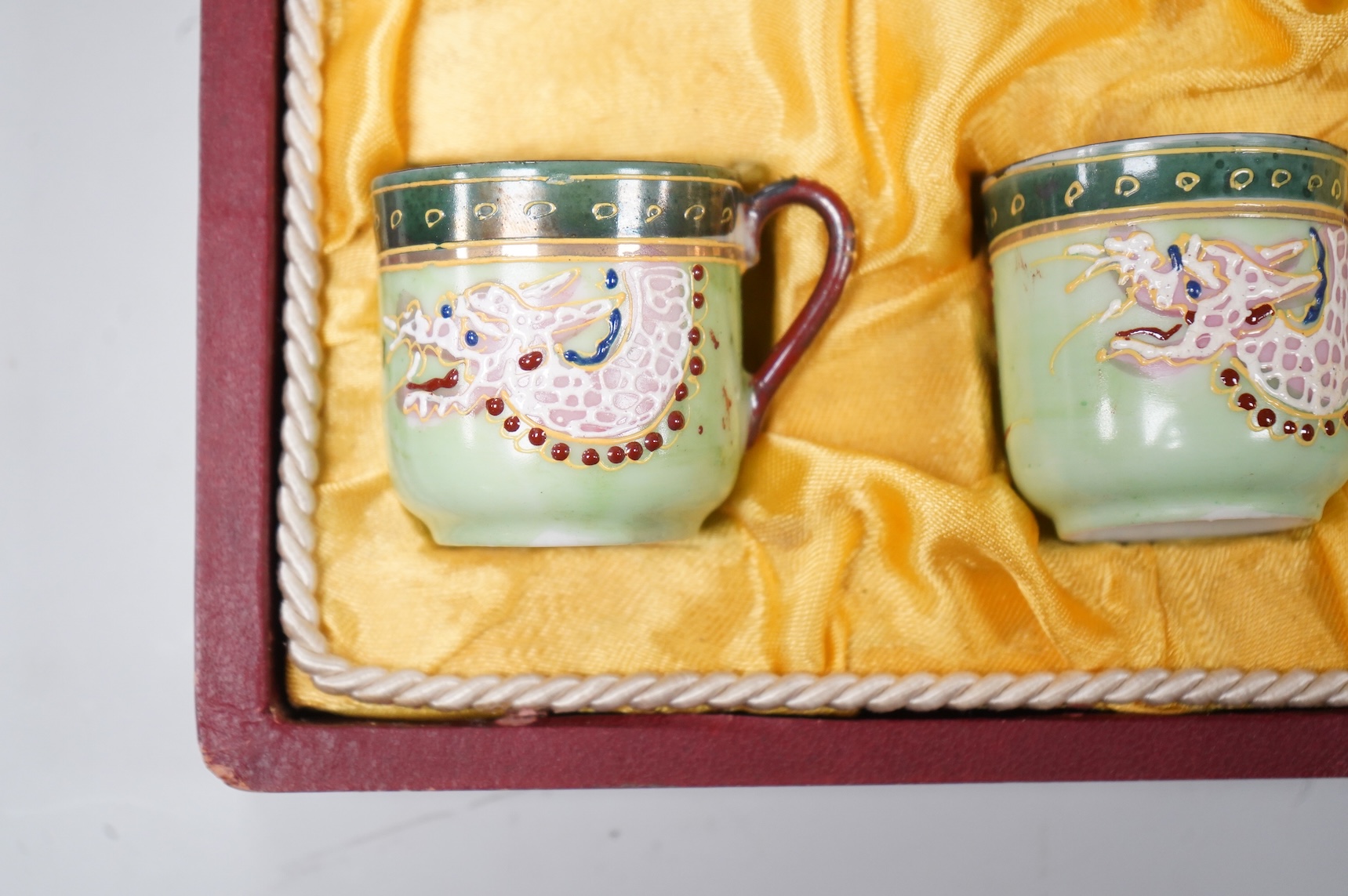 A cased Japanese coffee set, decorated with dragons on a green ground, case 34cm wide